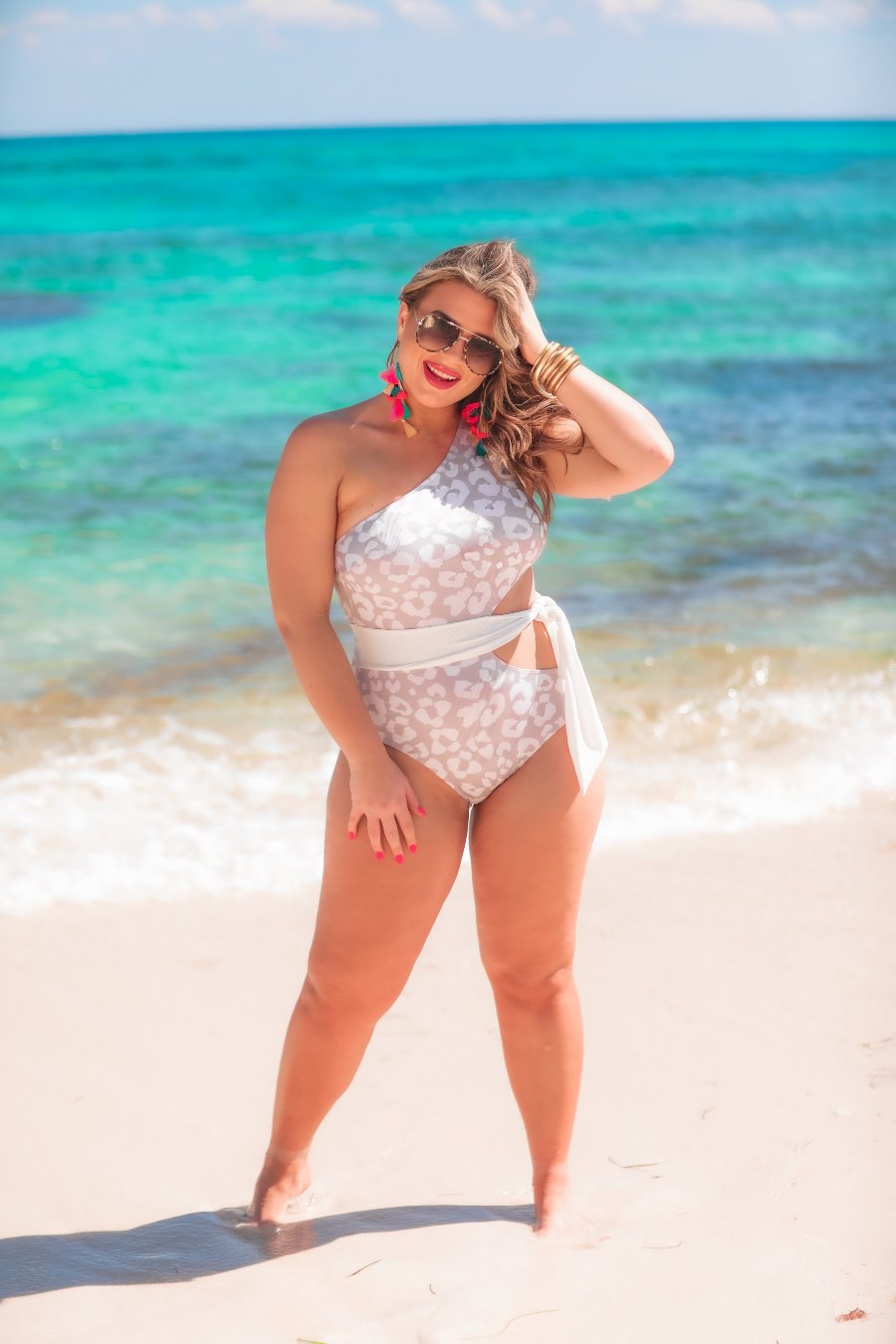 a one-shoulder one-piece swimsuit made of stretchy swim fabric with a flirty side cutout, wrap-around waist tie, removable padding, and a soft subtle leopard print