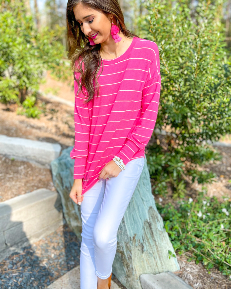 lightweight horizontal striped top with long sleeves, a crew neckline, and a slouched silhouette that ends in a rounded hemline on a solid pink base