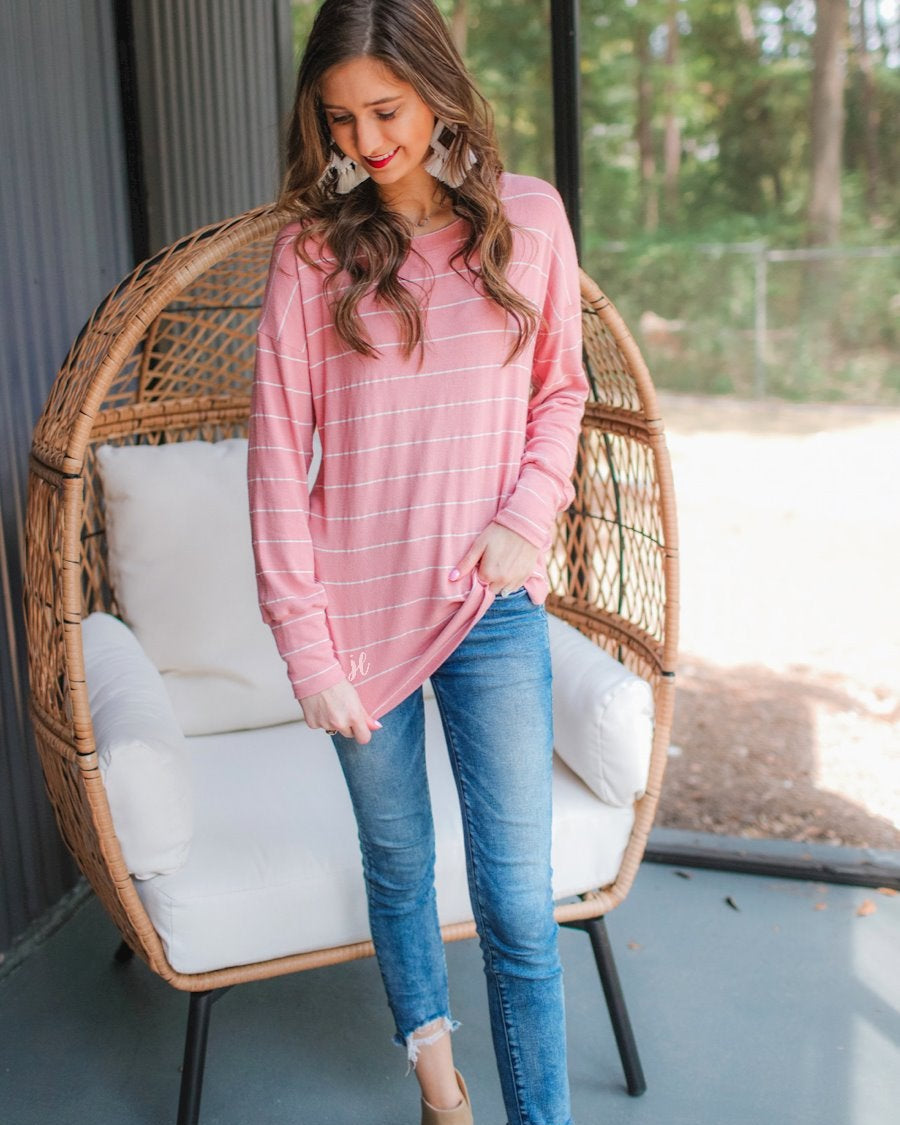 lightweight horizontal striped top with long sleeves, a crew neckline, and a slouched silhouette that ends in a rounded hemline on a solid mauve base