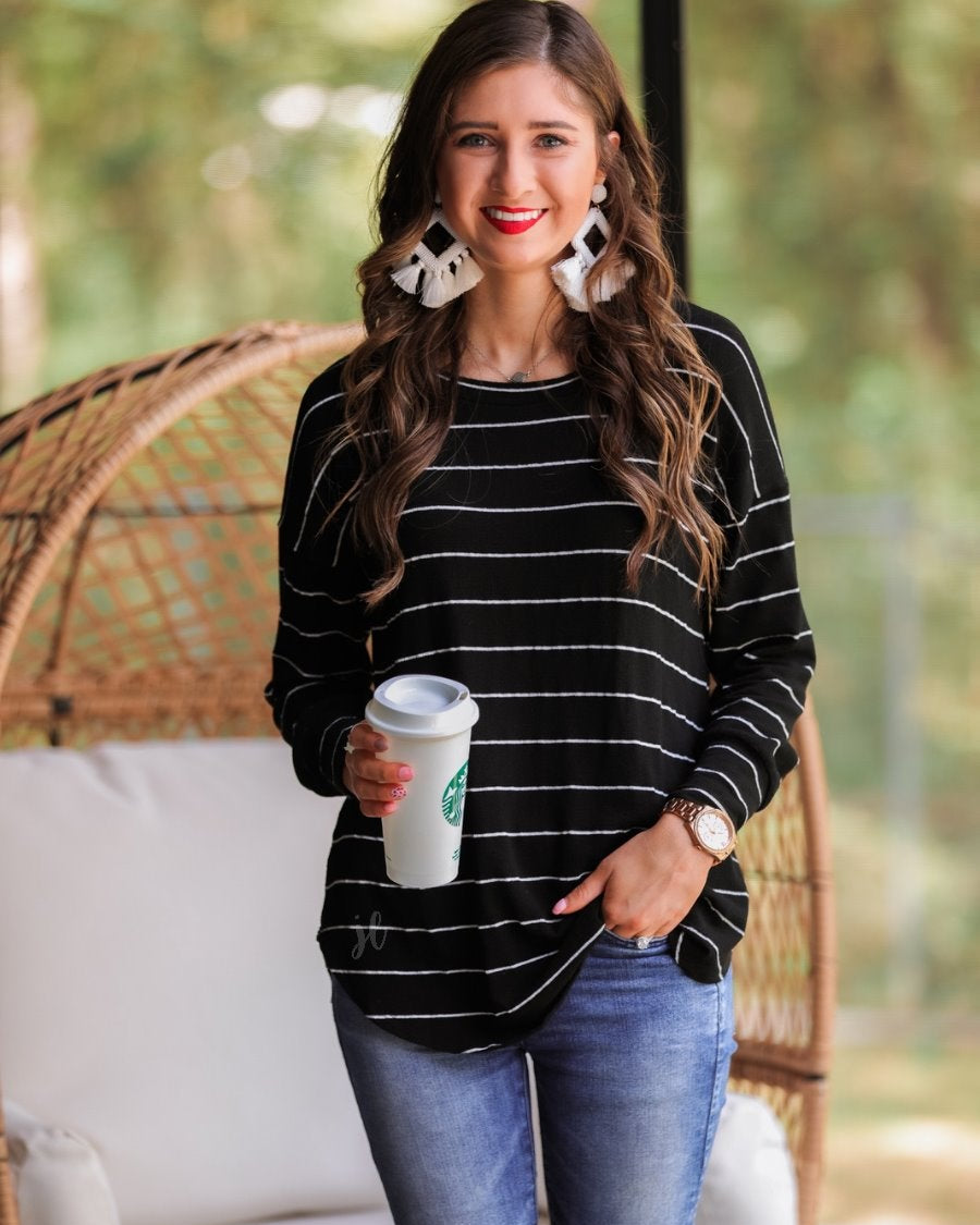 lightweight horizontal striped top with long sleeves, a crew neckline, and a slouched silhouette that ends in a rounded hemline on a solid black base
