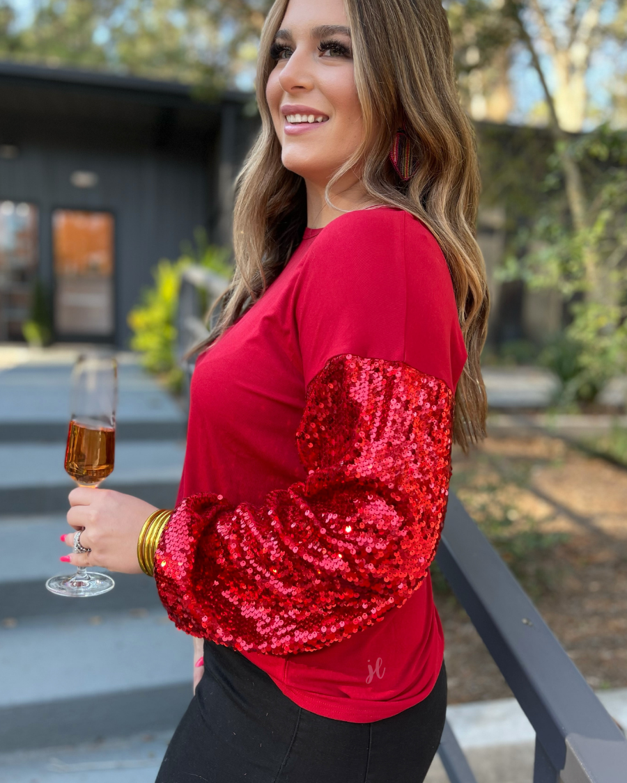 a red long-sleeve crewneck top with shimmering sequin balloon sleeves, a relaxed drop-shoulder silhouette, and softly gathered cuffs