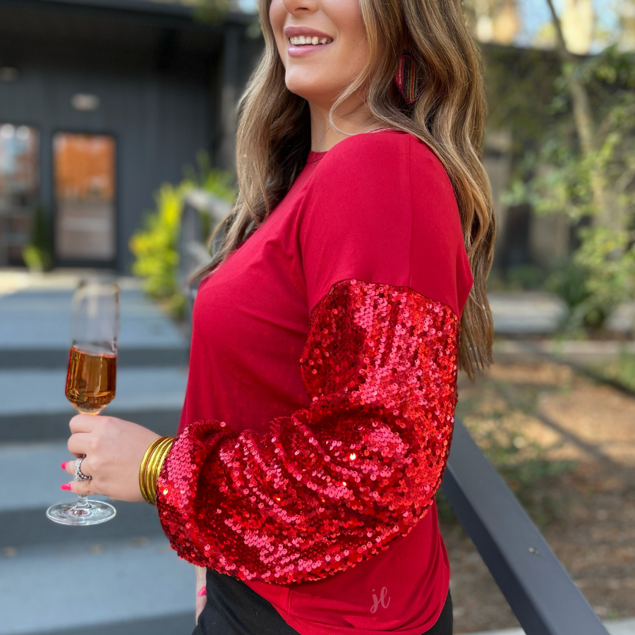 a red long-sleeve crewneck top with shimmering sequin balloon sleeves, a relaxed drop-shoulder silhouette, and softly gathered cuffs
