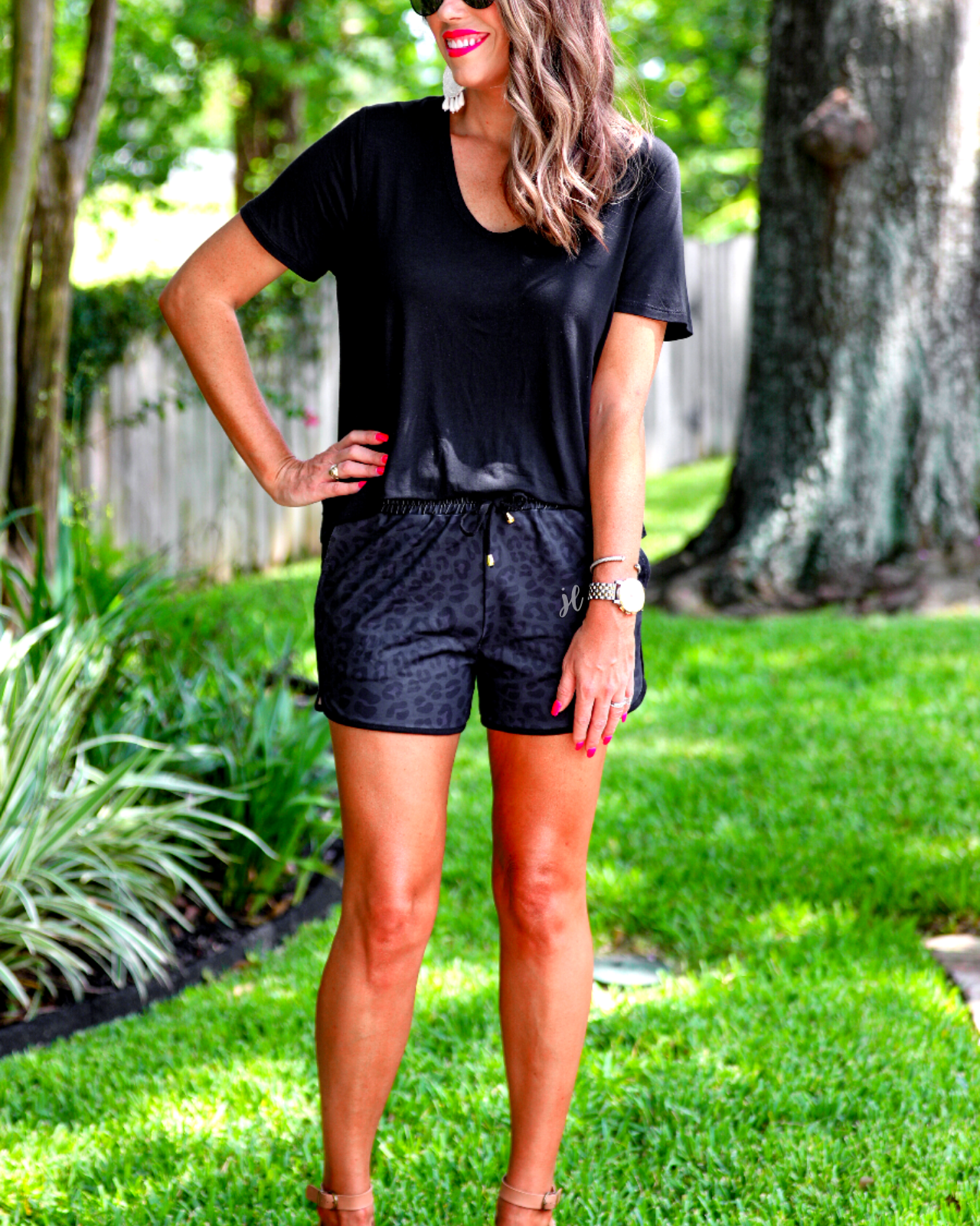 mid-rise relaxed fit activewear shorts with side pockets and a tie waist drawstring with gold bead accents, designed on a two-tone black leopard pattern print fabric, black base, and black trim