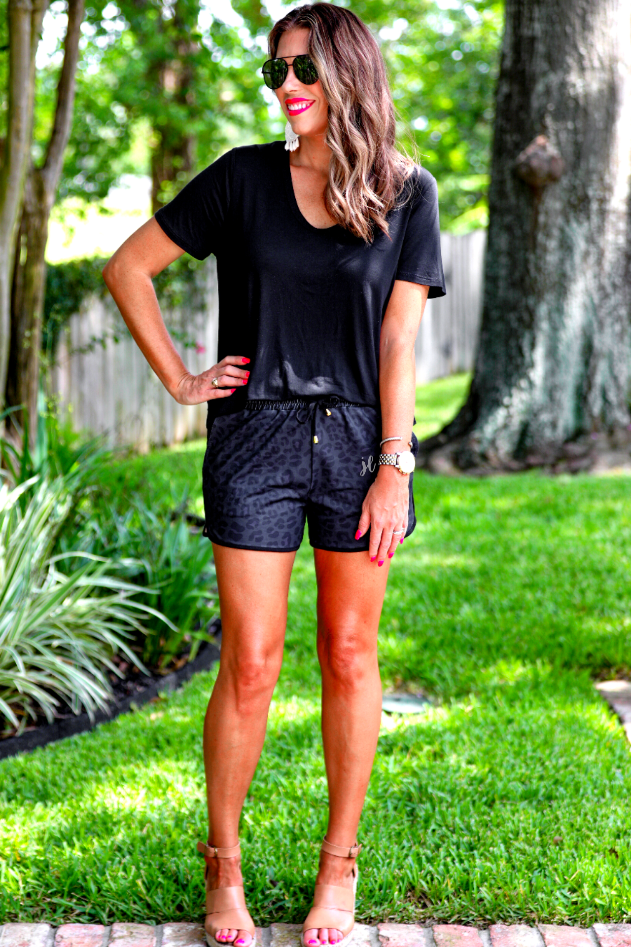 mid-rise relaxed fit activewear shorts with side pockets and a tie waist drawstring with gold bead accents, designed on a two-tone black leopard pattern print fabric, black base, and black trim