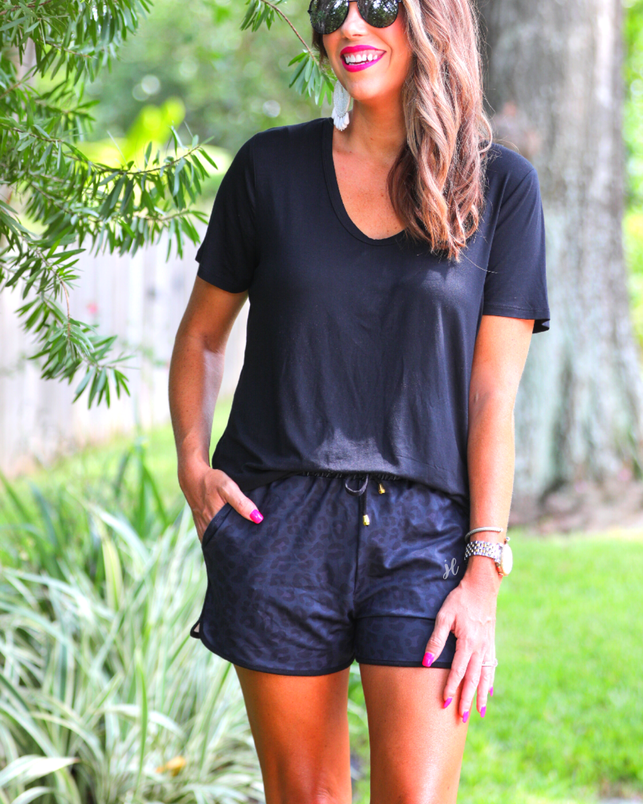 mid-rise relaxed fit activewear shorts with side pockets and a tie waist drawstring with gold bead accents, designed on a two-tone black leopard pattern print fabric, black base, and black trim