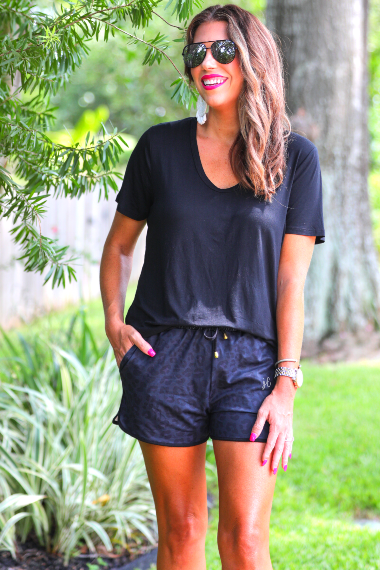 mid-rise relaxed fit activewear shorts with side pockets and a tie waist drawstring with gold bead accents, designed on a two-tone black leopard pattern print fabric, black base, and black trim