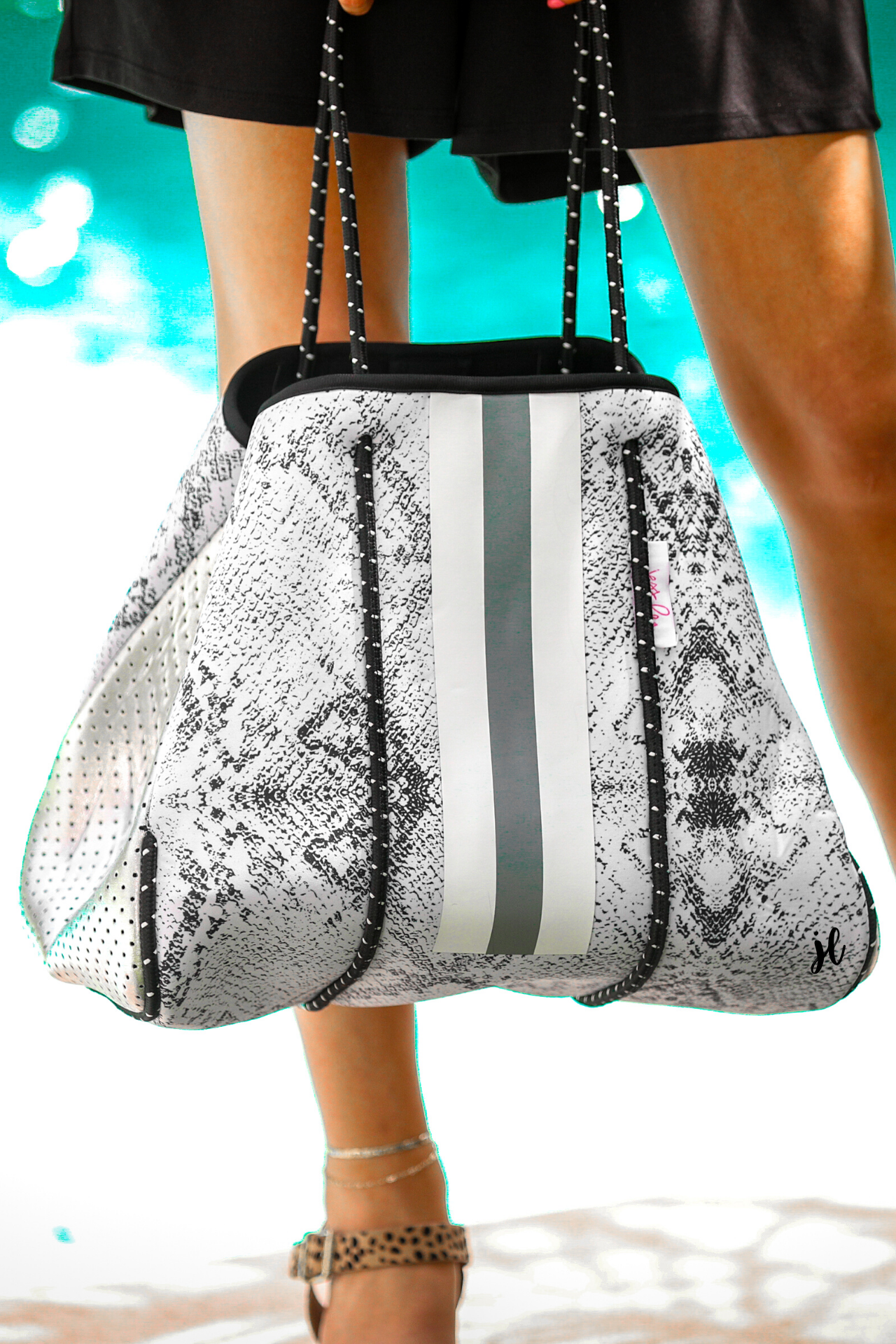 ultra-lightweight tote made of neoprene with a removable hard bottom liner, paracord shoulder straps, removable matching zippered pouch, magnetic side snap closures in silver hardware, black interior (tote and pouch), and racing stripes (gray and white)