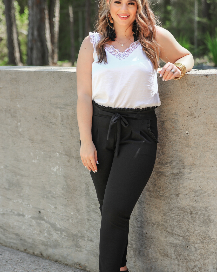 high-waisted paper-bag silhouette pants with a ruffle trim and sash tie, lightweight drapey fabric, straight legs, side pockets polished with a flirty ruffle, and unlined for breezy comfort in black