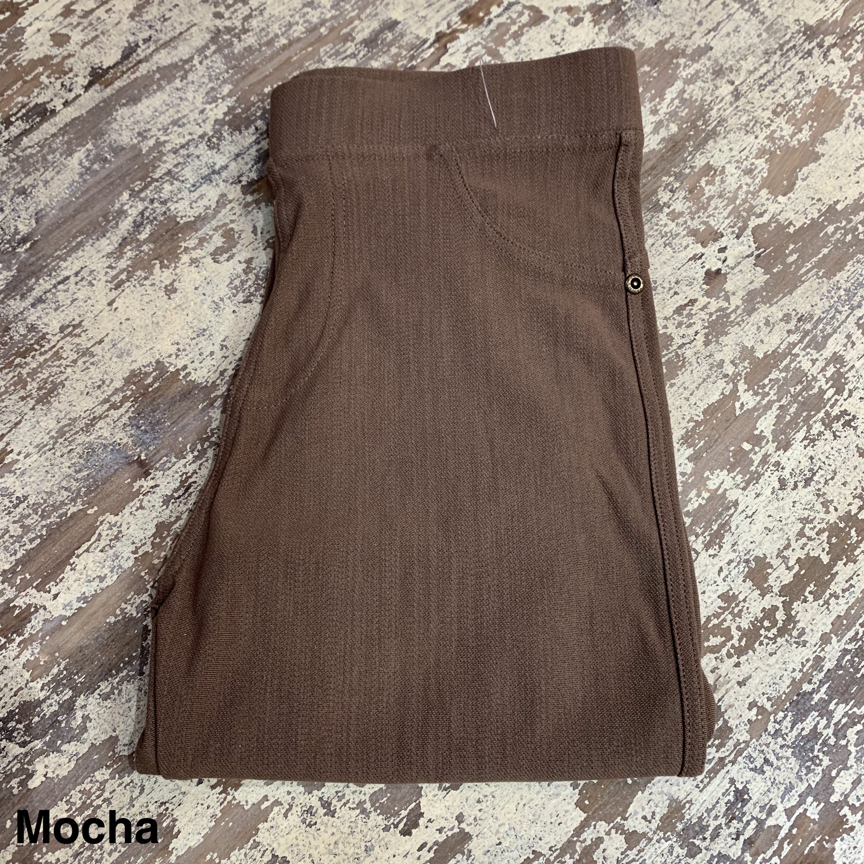 solid pull-on style leggings made of premium stretch fabric thicker than regular leggings, an elastic waistband, double back pockets, and a unique stripe detailing on the inside in mocha