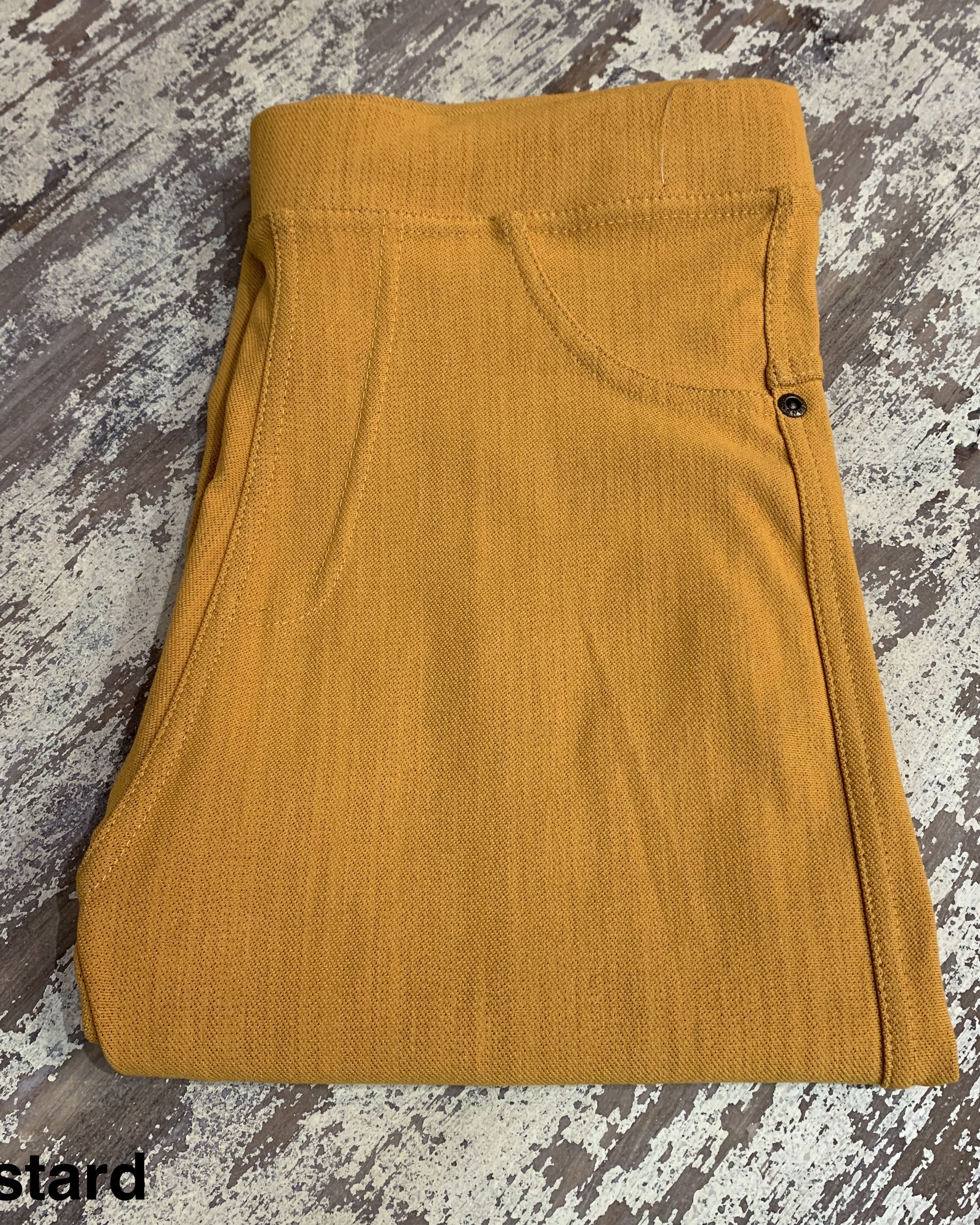 solid pull-on style leggings made of premium stretch fabric thicker than regular leggings, an elastic waistband, double back pockets, and a unique stripe detailing on the inside in mustard