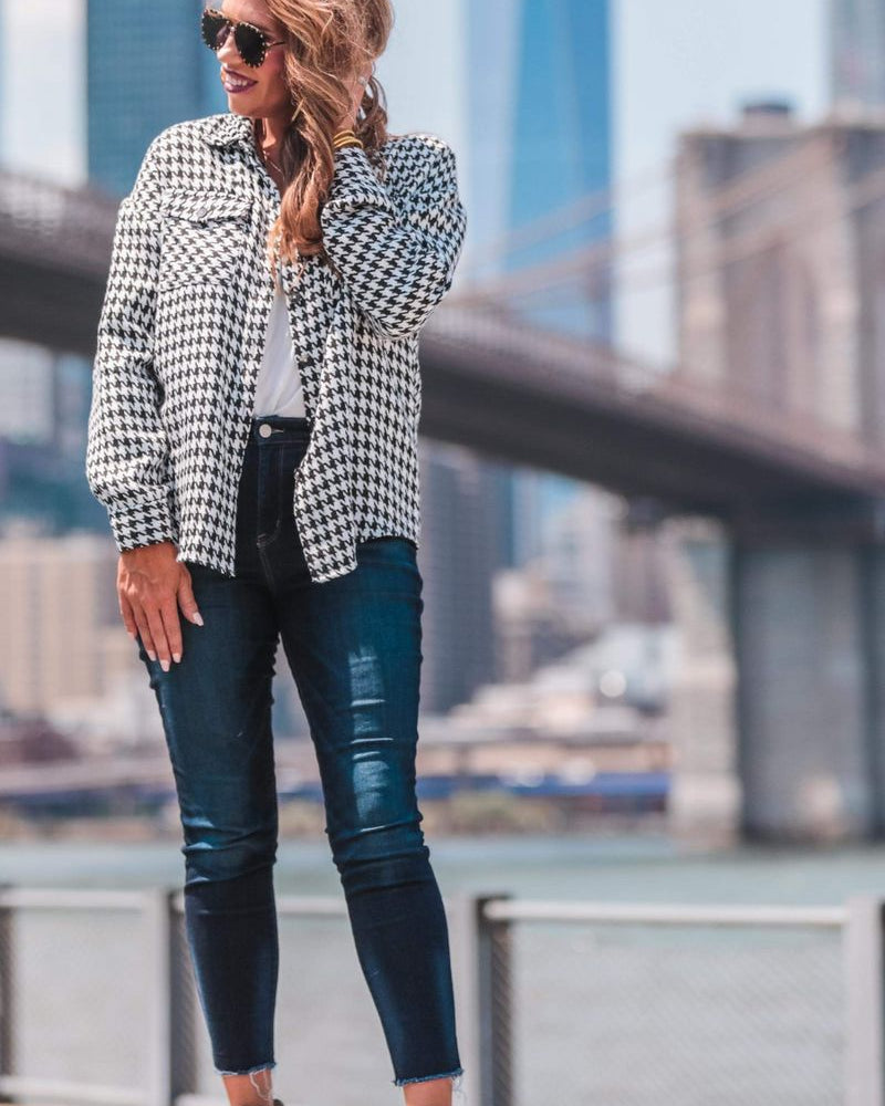 long sleeve drop shoulder shacket with button closures, a button-down front, a collared neckline, chest pockets, and back detailing on a black and white houndstooth print