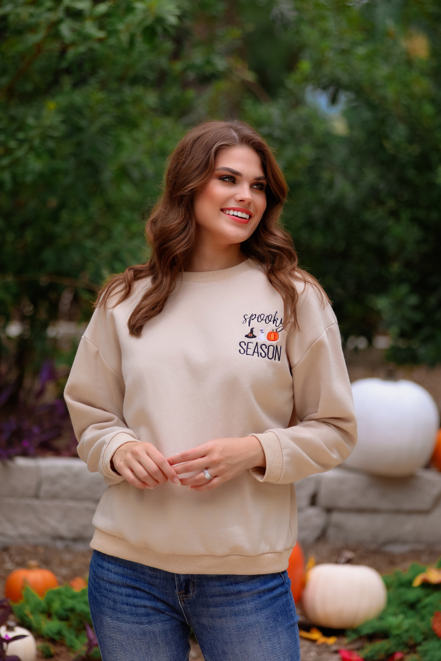 a tan long-sleeve sweatshirt crafted from soft fabric with black embroidered 'spooky SEASON' chest lettering, mini witch hat, ghost, and pumpkin accents, crew neckline, dropped shoulders, ribbed cuffs, banded hem, and a relaxed fit