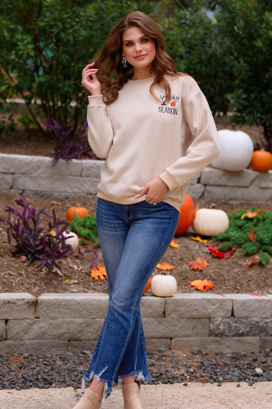 a tan long-sleeve sweatshirt crafted from soft fabric with black embroidered 'spooky SEASON' chest lettering, mini witch hat, ghost, and pumpkin accents, crew neckline, dropped shoulders, ribbed cuffs, banded hem, and a relaxed fit