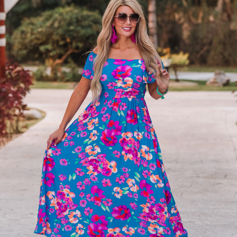 an off-the-shoulder floral dress made of lightweight material with ruffle sleeves, a stretchy smocked back, and interior lining in blue