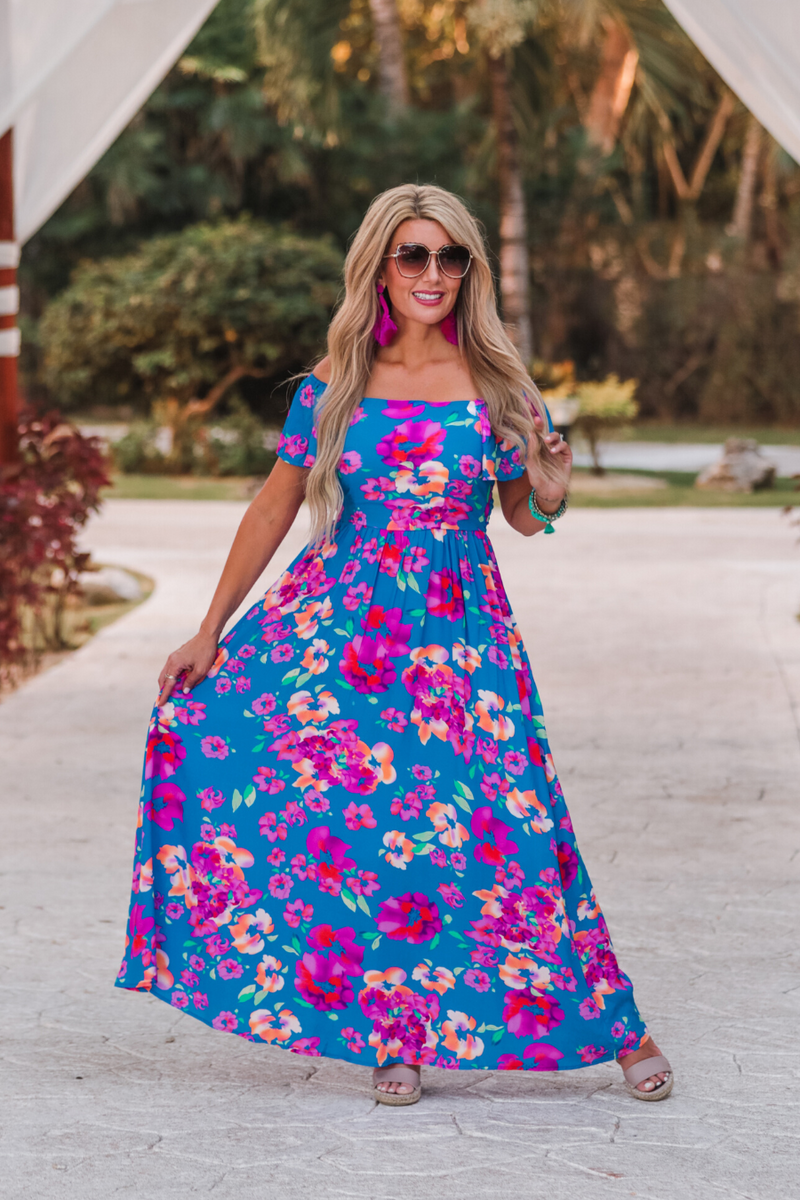 an off-the-shoulder floral dress made of lightweight material with ruffle sleeves, a stretchy smocked back, and interior lining in blue