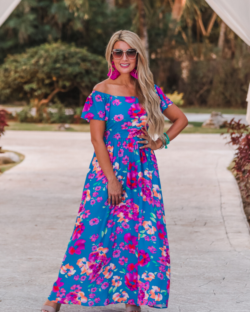 an off-the-shoulder floral dress made of lightweight material with ruffle sleeves, a stretchy smocked back, and interior lining in blue