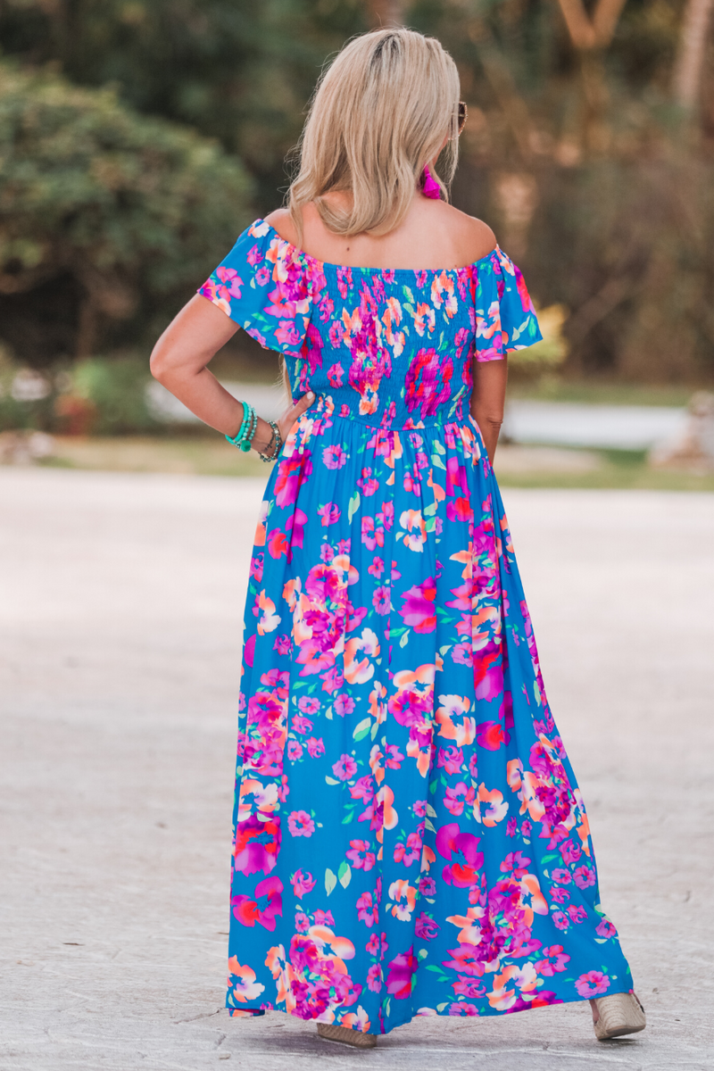 an off-the-shoulder floral dress made of lightweight material with ruffle sleeves, a stretchy smocked back, and interior lining in blue