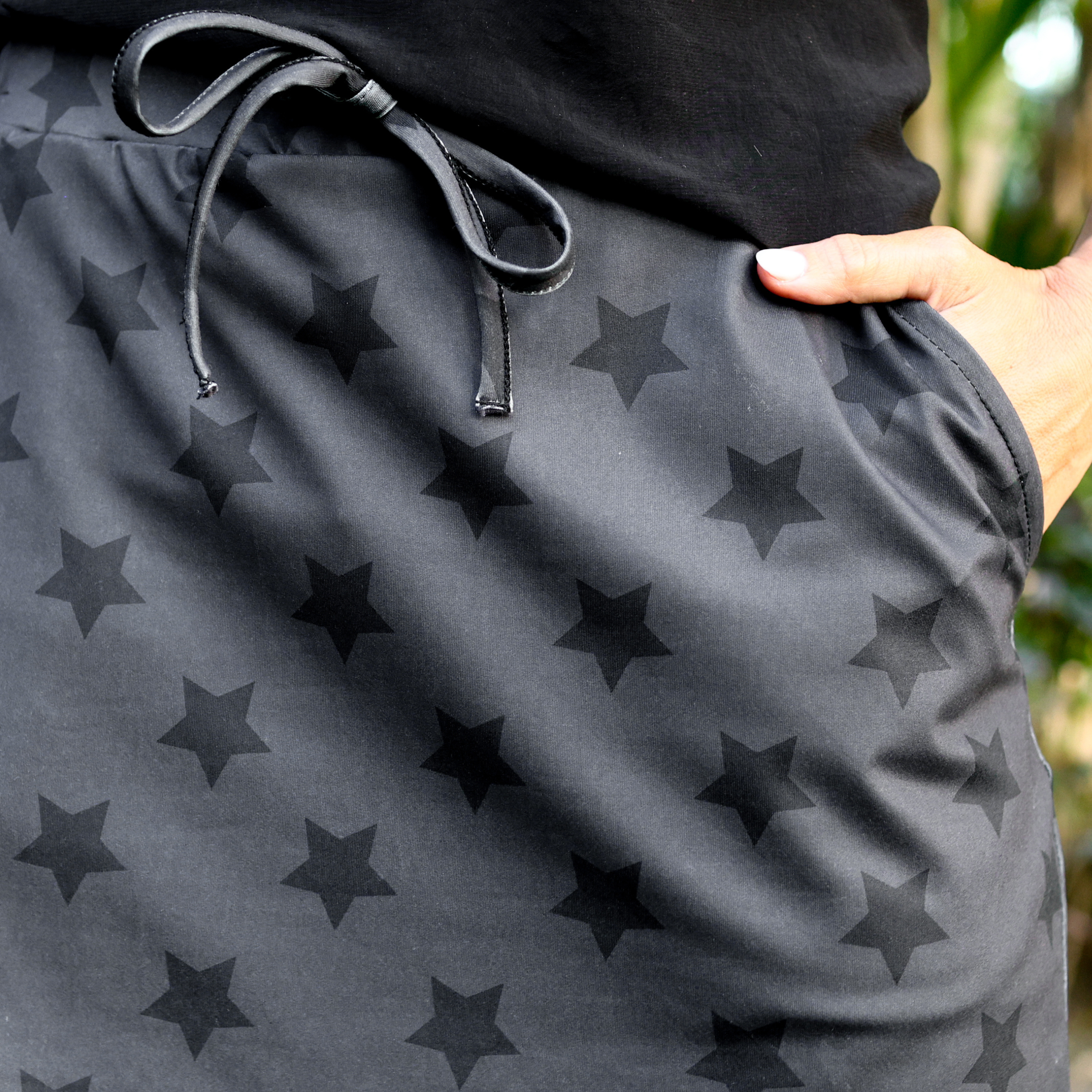 mid-rise relaxed fit everyday skort made of lightweight material with built-in black shorts, drawstring tie, an elastic band on the back, and side pockets, designed on a two-tone black star pattern print