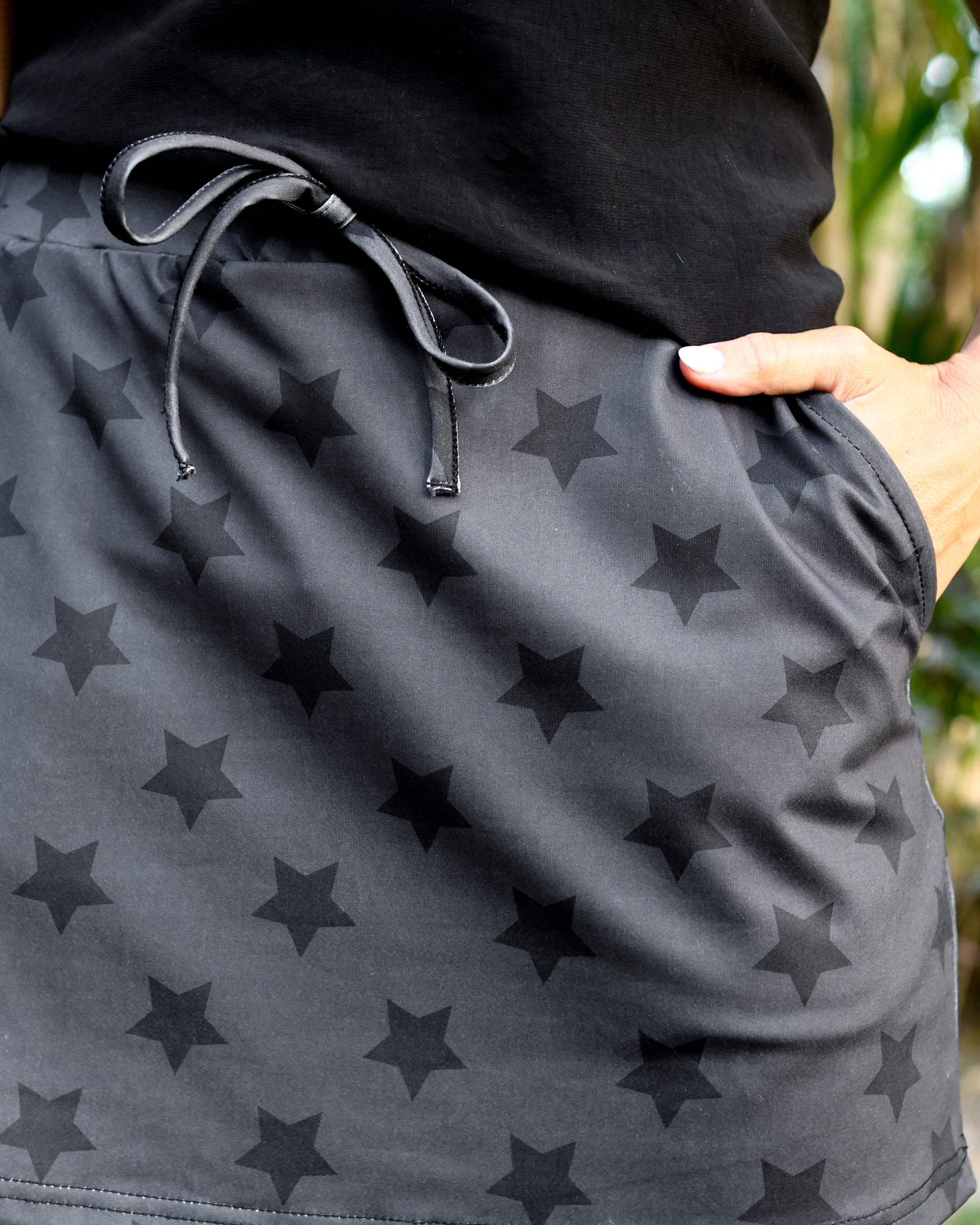 mid-rise relaxed fit everyday skort made of lightweight material with built-in black shorts, drawstring tie, an elastic band on the back, and side pockets, designed on a two-tone black star pattern print