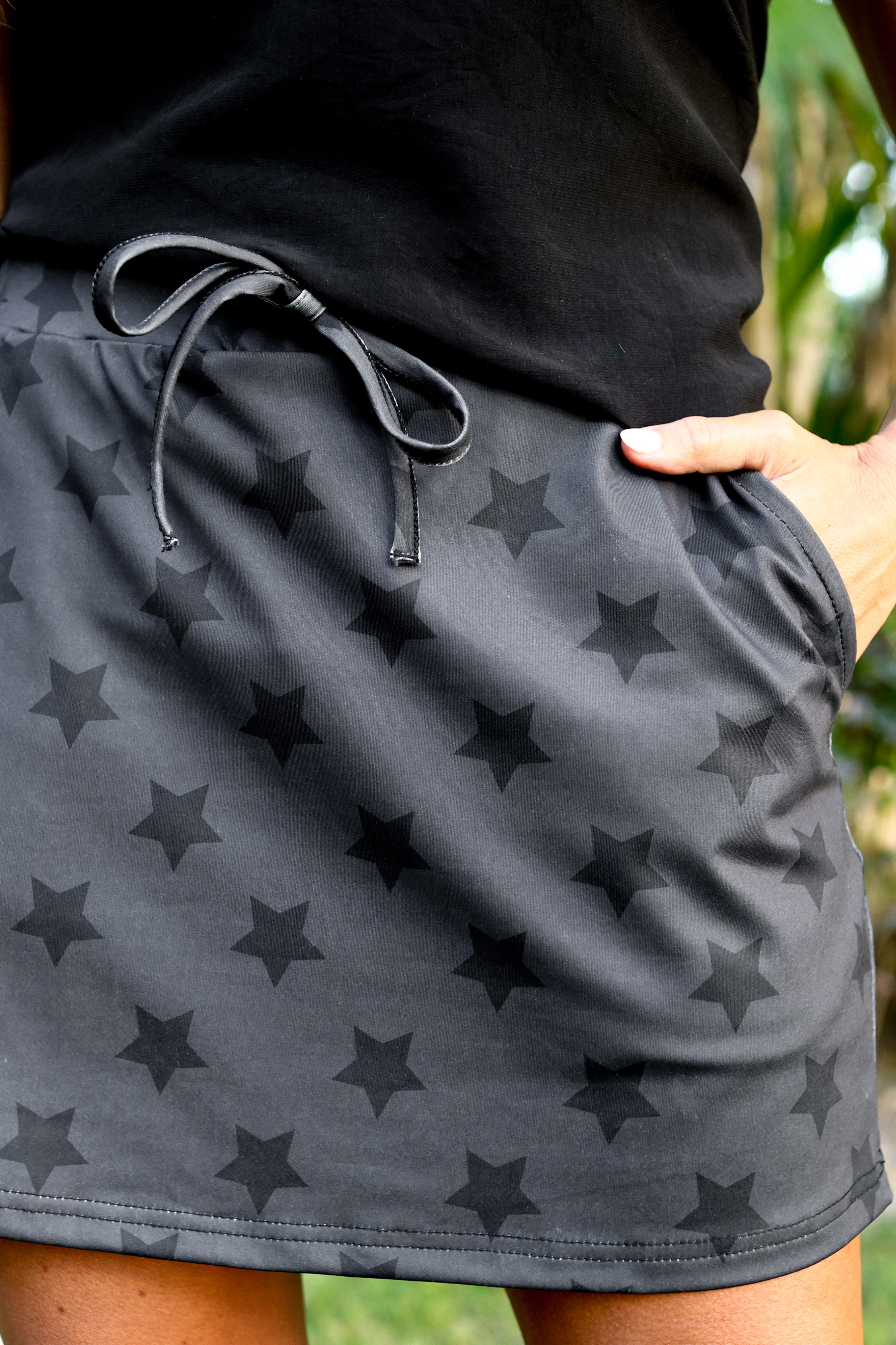 mid-rise relaxed fit everyday skort made of lightweight material with built-in black shorts, drawstring tie, an elastic band on the back, and side pockets, designed on a two-tone black star pattern print