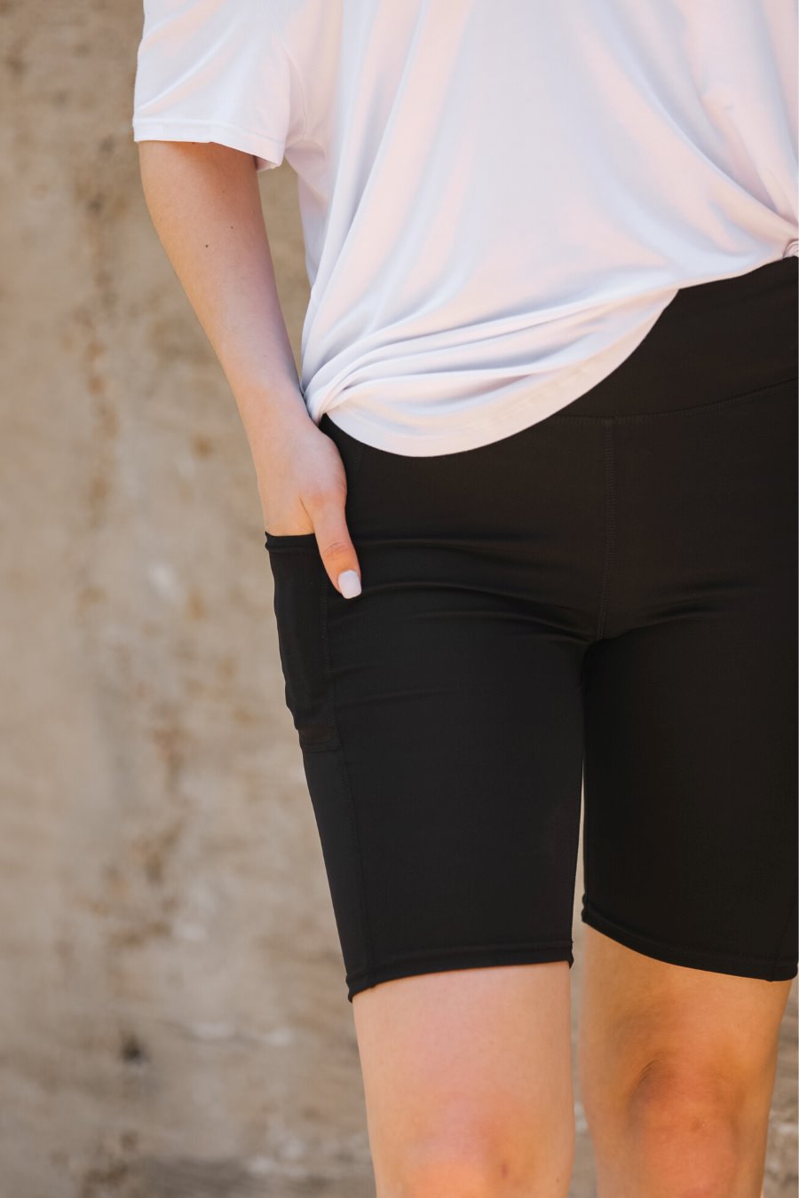 sleek black biker shorts crafted from lightweight stretch fabric with a high elastic waistband for tummy control, side pockets, a flattering figure-hugging short silhouette, above-knee length, and pull-on design