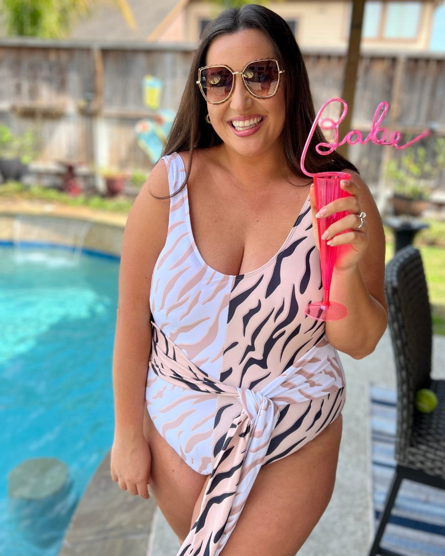 a one-piece swimsuit made of stretchy material with a scoop back, chunky straps, a versatile accent tie, and removable padding on a neutral color block animal print pattern fabric