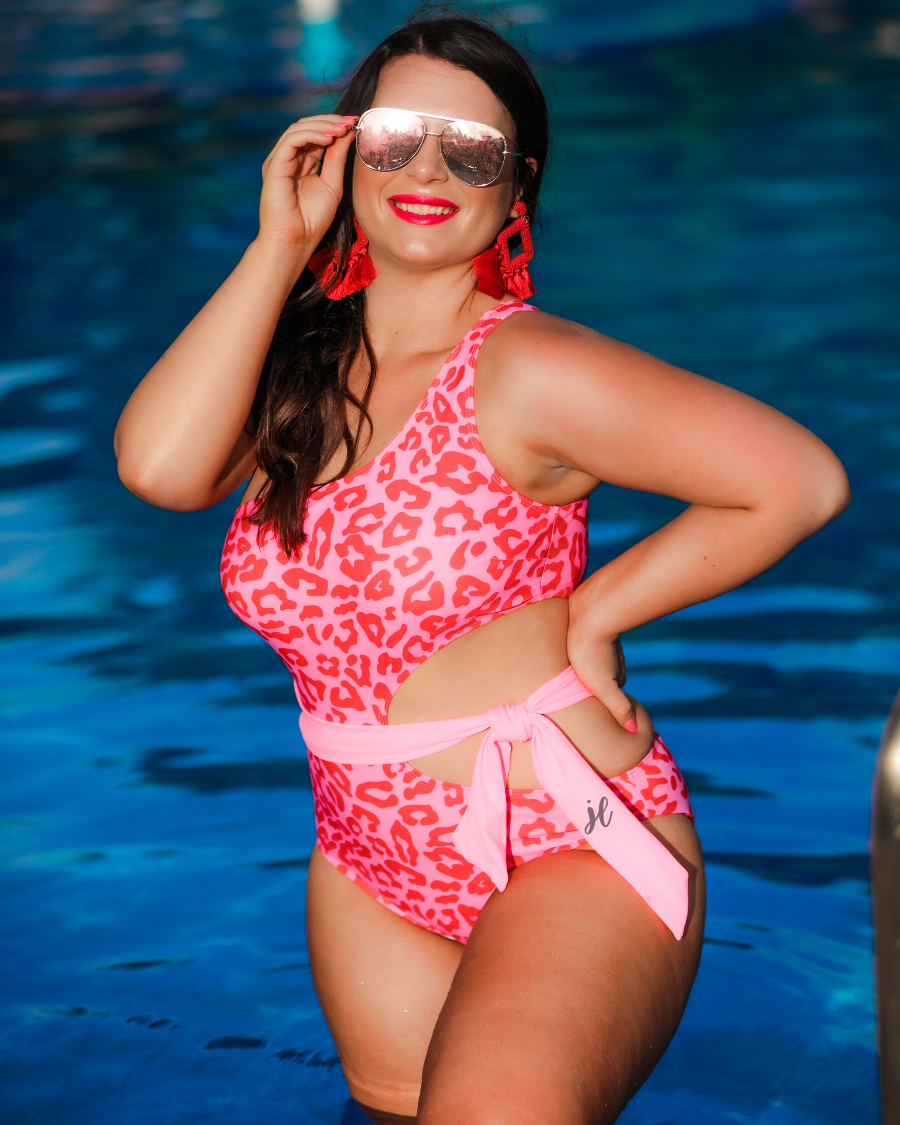 one-shoulder swimsuit made of stretchy material with a side cutout, a wrap-around tie, and removable padding on a two-toned pink leopard print fabric