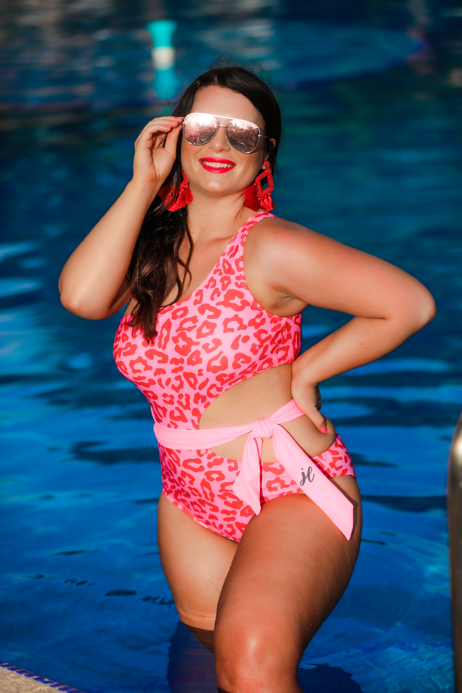 one-shoulder swimsuit made of stretchy material with a side cutout, a wrap-around tie, and removable padding on a two-toned pink leopard print fabric