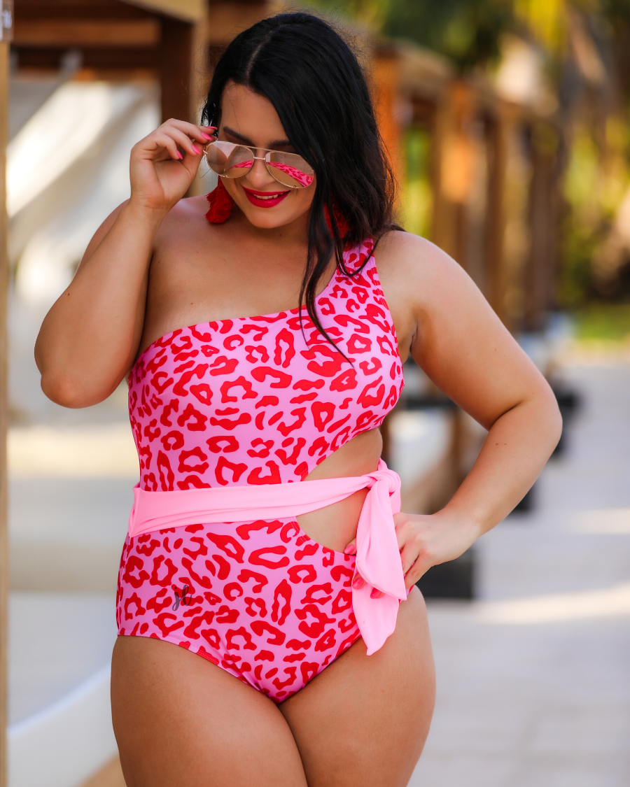 one-shoulder swimsuit made of stretchy material with a side cutout, a wrap-around tie, and removable padding on a two-toned pink leopard print fabric