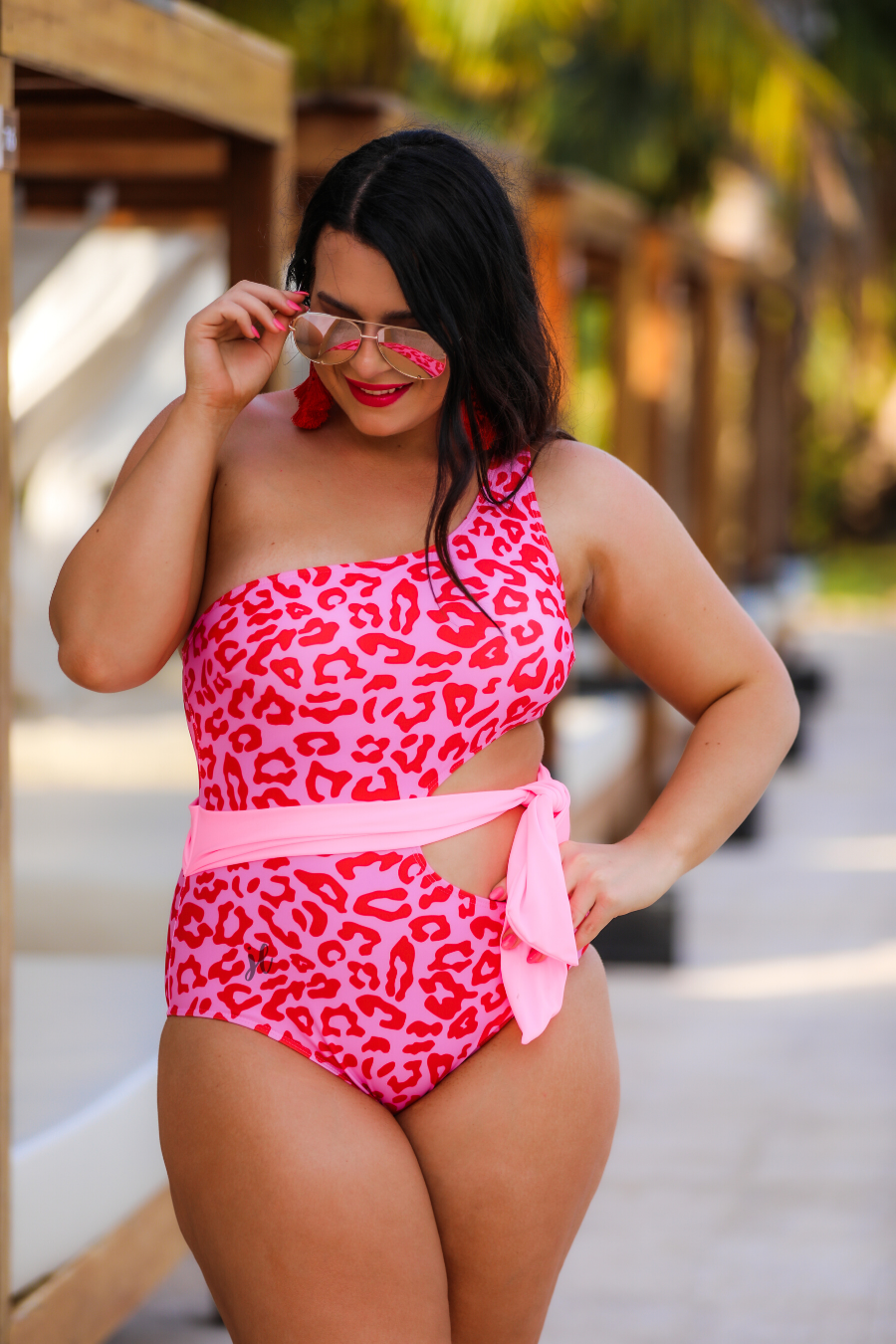 one-shoulder swimsuit made of stretchy material with a side cutout, a wrap-around tie, and removable padding on a two-toned pink leopard print fabric