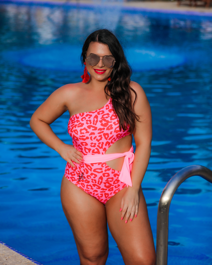 one-shoulder swimsuit made of stretchy material with a side cutout, a wrap-around tie, and removable padding on a two-toned pink leopard print fabric