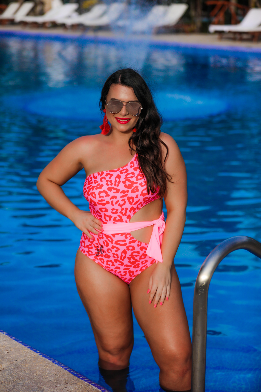one-shoulder swimsuit made of stretchy material with a side cutout, a wrap-around tie, and removable padding on a two-toned pink leopard print fabric