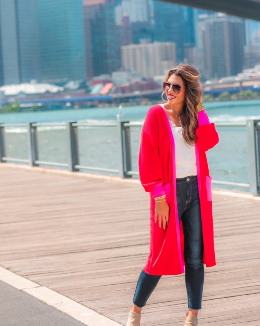 a long-sleeve cardigan with an open-front silhouette, bold pink and red color blocking, contrast cuffs, chic trim detailing, functional side pockets, and a relaxed straight fit