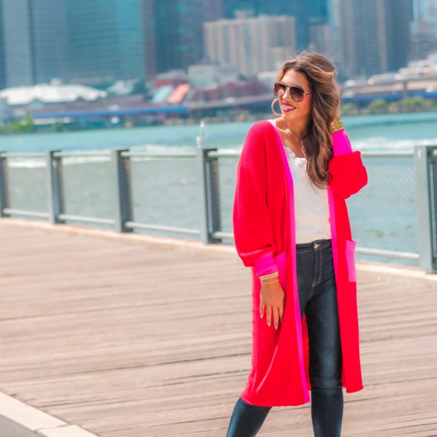 a long-sleeve cardigan with an open-front silhouette, bold pink and red color blocking, contrast cuffs, chic trim detailing, functional side pockets, and a relaxed straight fit