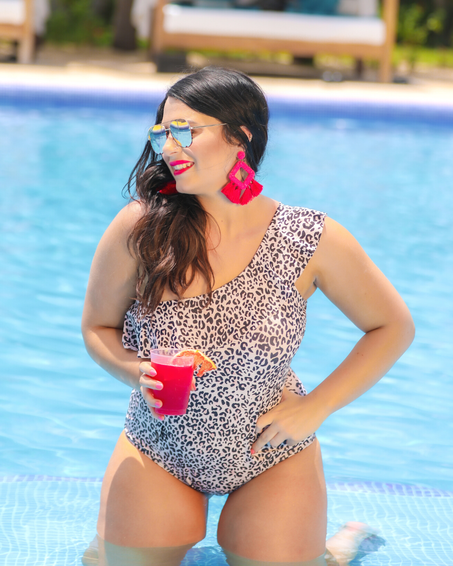 a one-piece swimsuit made from stretchy swim fabric with a black and neutral leopard print, one-shoulder ruffled neckline, and removable padding