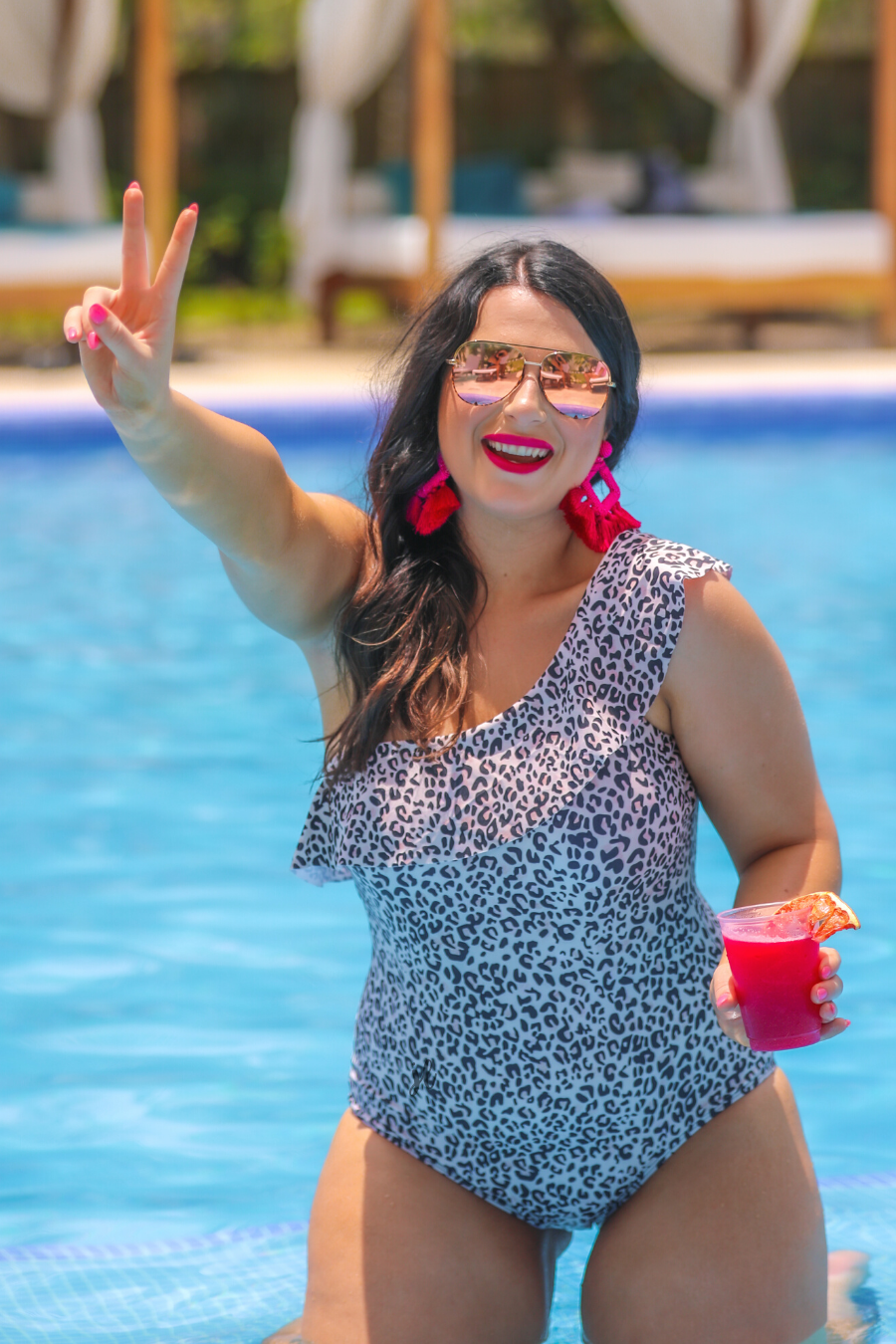 a one-piece swimsuit made from stretchy swim fabric with a black and neutral leopard print, one-shoulder ruffled neckline, and removable padding