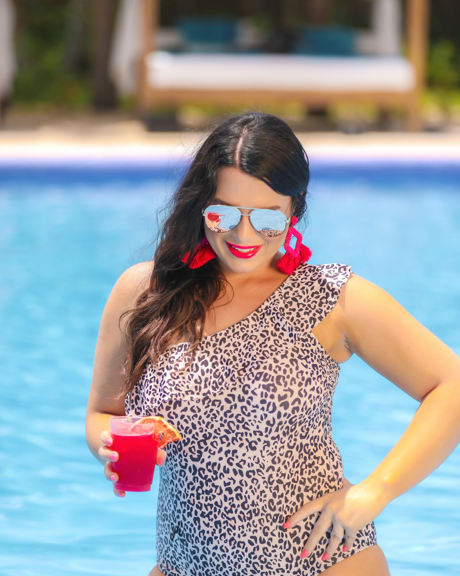 a one-piece swimsuit made from stretchy swim fabric with a black and neutral leopard print, one-shoulder ruffled neckline, and removable padding