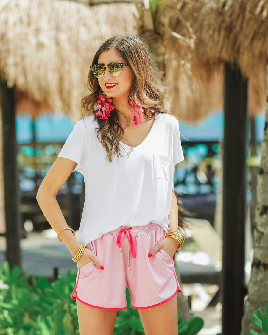 mid-rise relaxed fit activewear shorts with side pockets and a tie waist drawstring with gold bead accents, designed on a solid light print fabric and hot pink trim