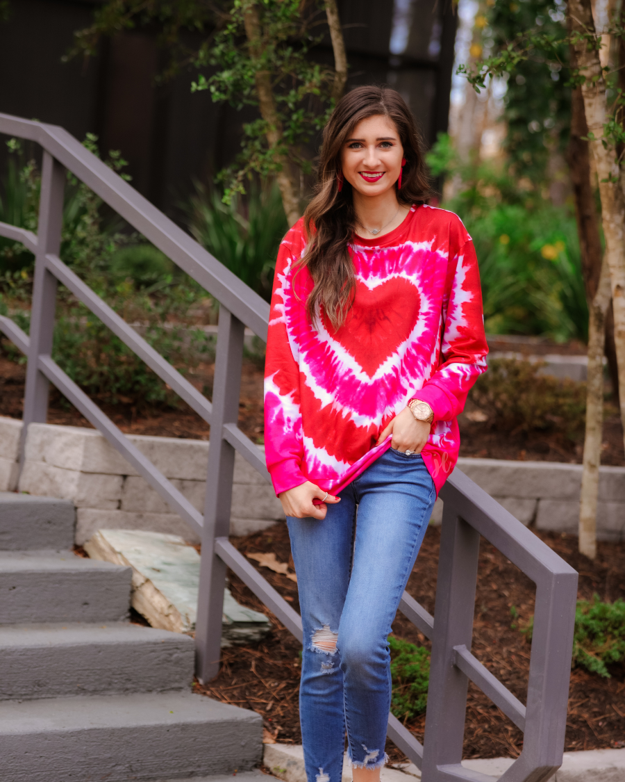 a red lightweight long-sleeve knit top with a bold heart motif layered over a vibrant tie-dye pattern, a flattering scoop neckline, and a streamlined silhouette that finished with a straight hem