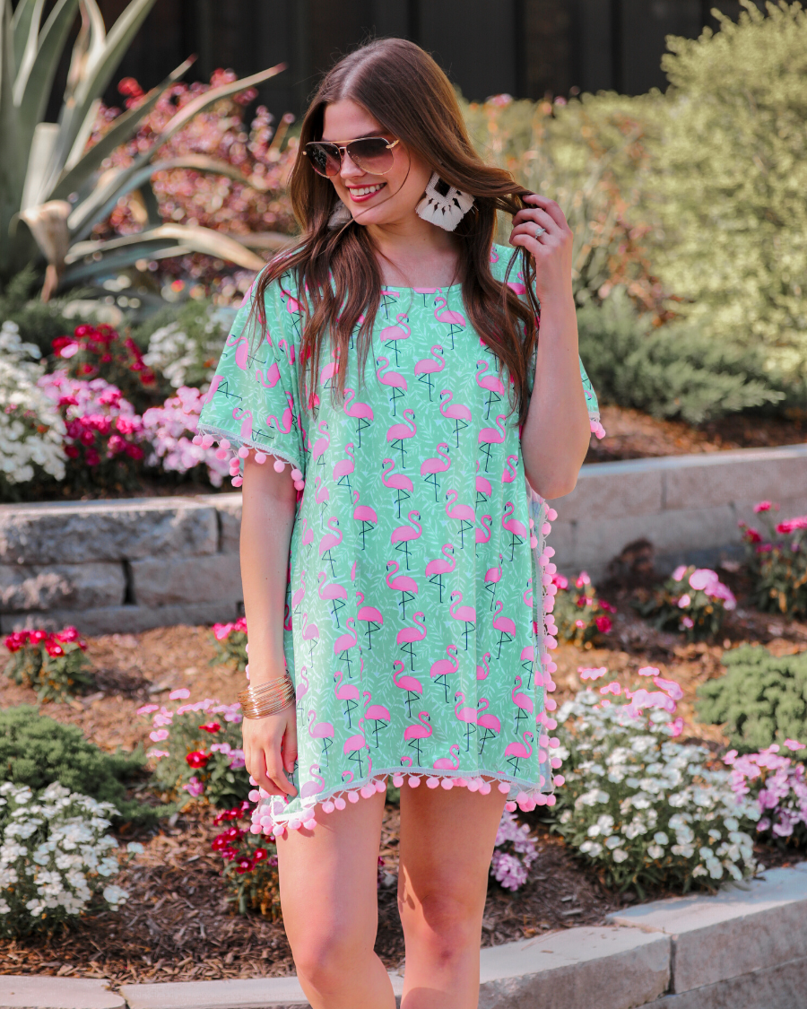 lightweight coverup made of breezy material with playful light pink pom pom decorative trim and fun pink flamingo print on a mint background