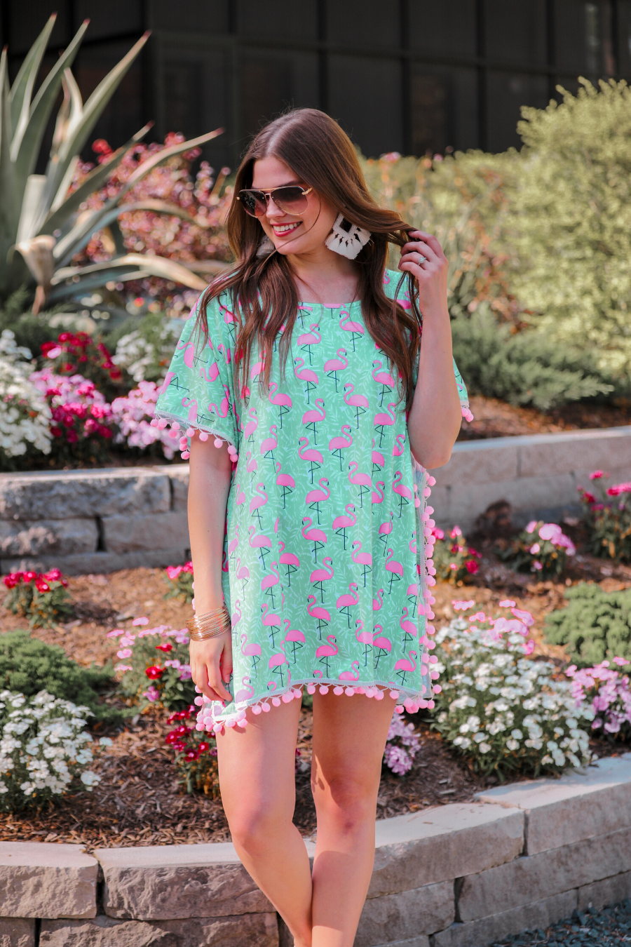 lightweight coverup made of breezy material with playful light pink pom pom decorative trim and fun pink flamingo print on a mint background