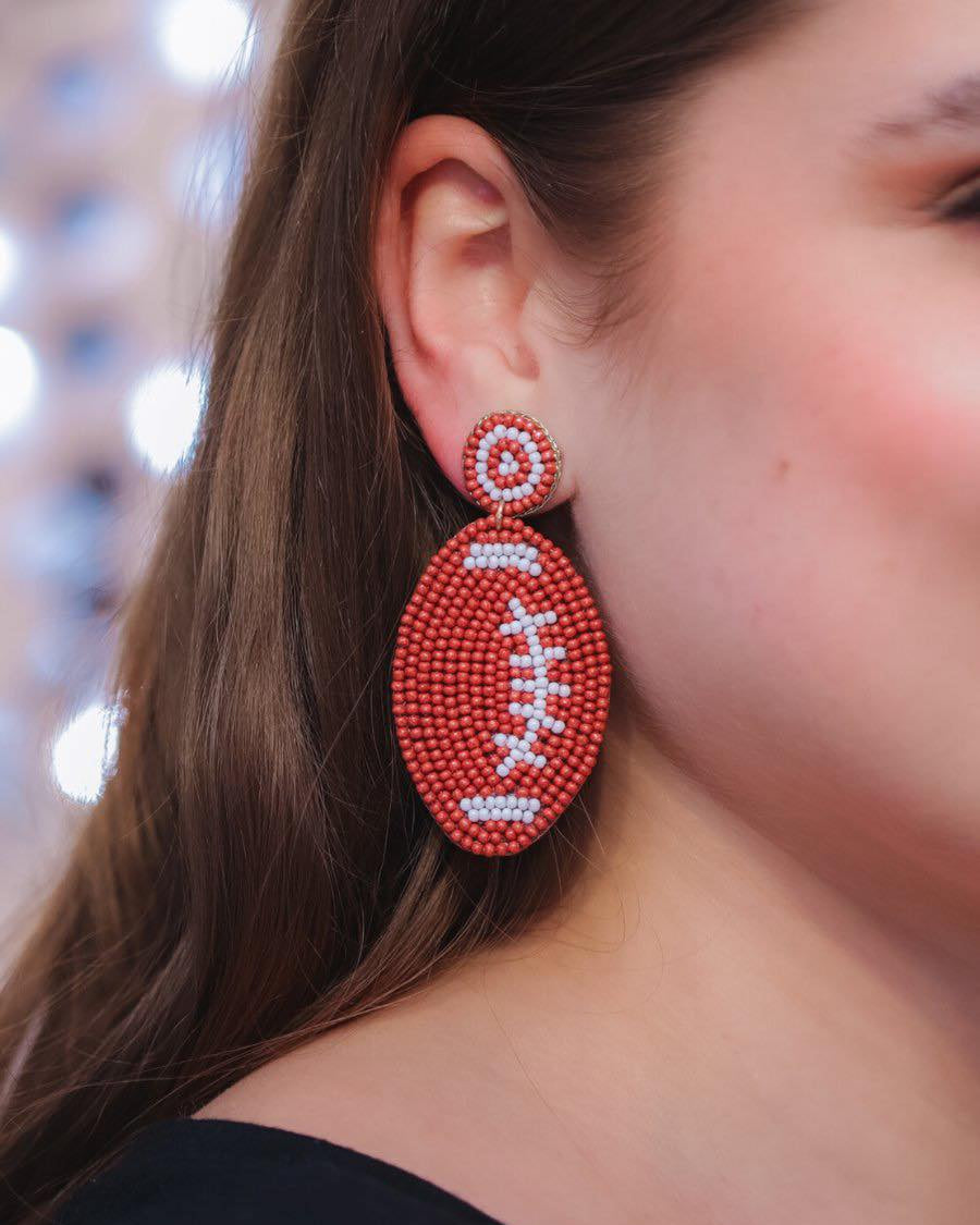 ultra-lightweight post-stud earrings with a brown and white beaded football design, a felt backing, comfort replacement earring backs, and a plastic disk stopper style in gold