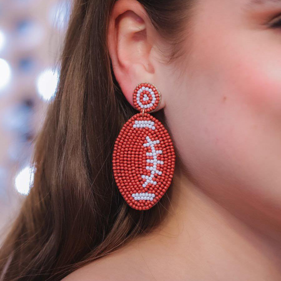 ultra-lightweight post-stud earrings with a brown and white beaded football design, a felt backing, comfort replacement earring backs, and a plastic disk stopper style in gold