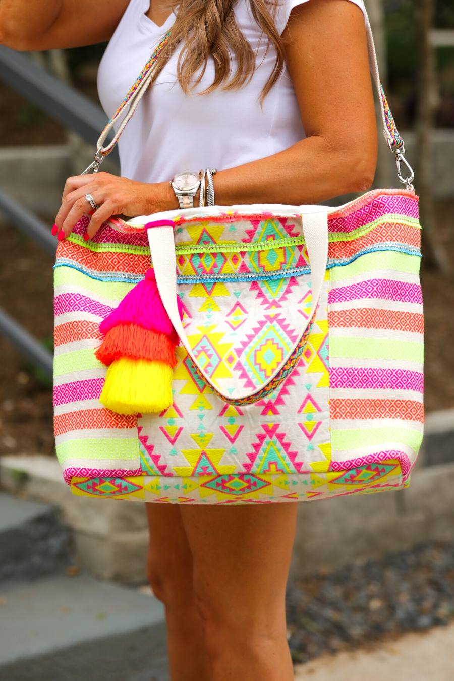 double-handle canvas bag with a removable three-tier neon tassel (pink, orange, and yellow), full-zipper closure, a removable adjustable strap (bohemian trim ribbon braid), and interior pockets (two open, one zip) on a geometric and stripe multicolor pattern print