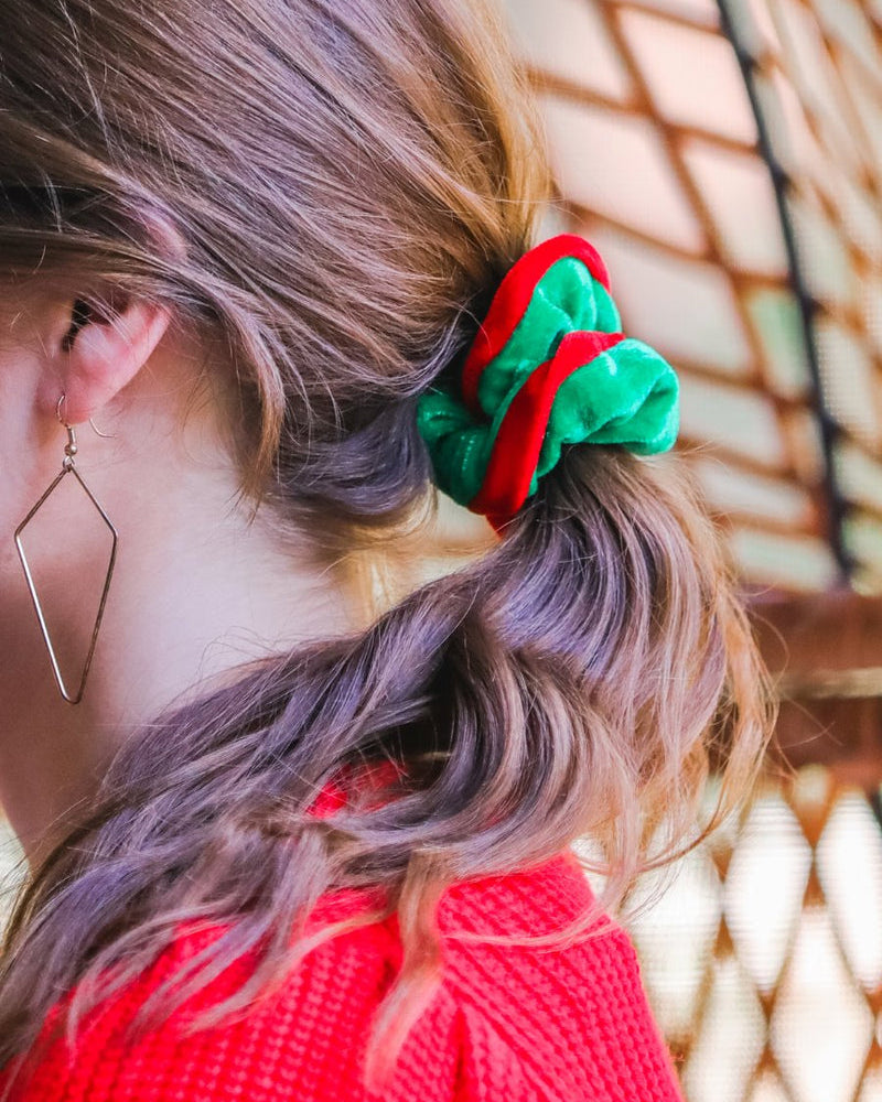 a plush velvet scrunchie in a rich nostalgic colorway (classic green with red trim) with contrasting trim and comfortable elastic
