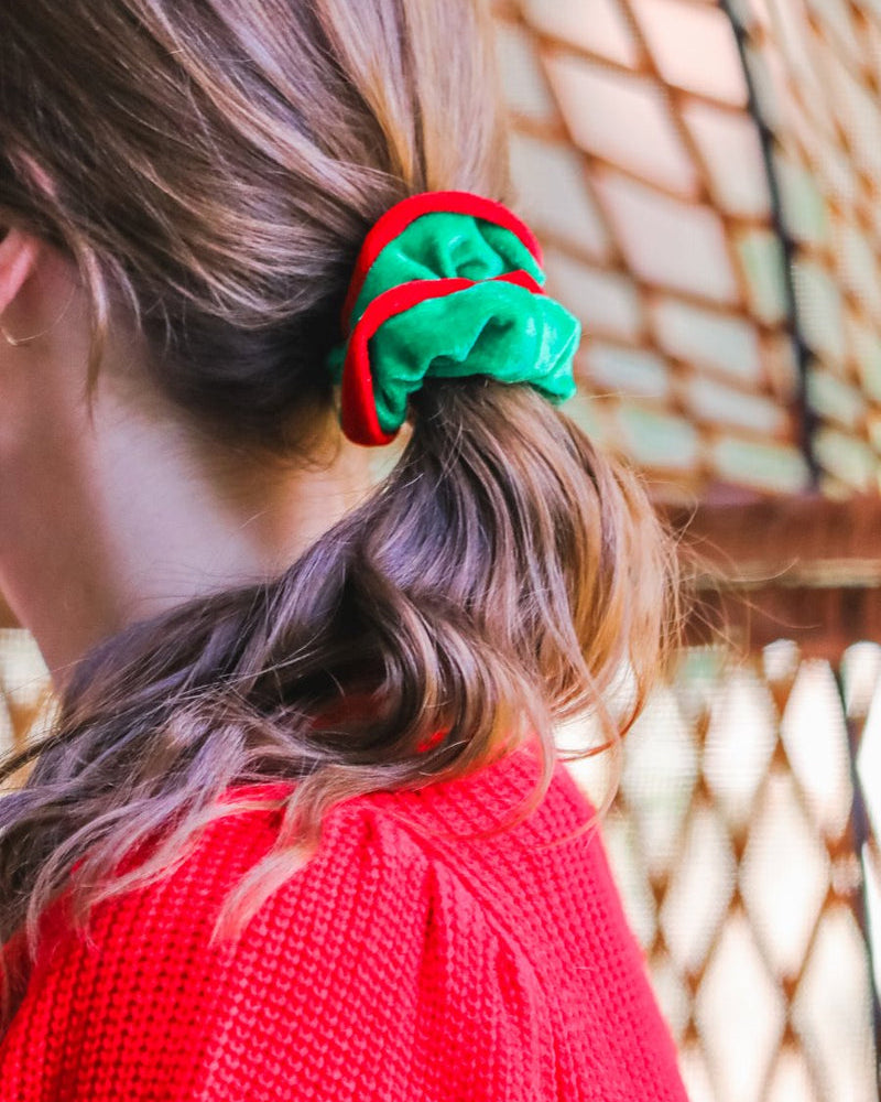 a plush velvet scrunchie in a rich nostalgic colorway (classic green with red trim) with contrasting trim and comfortable elastic