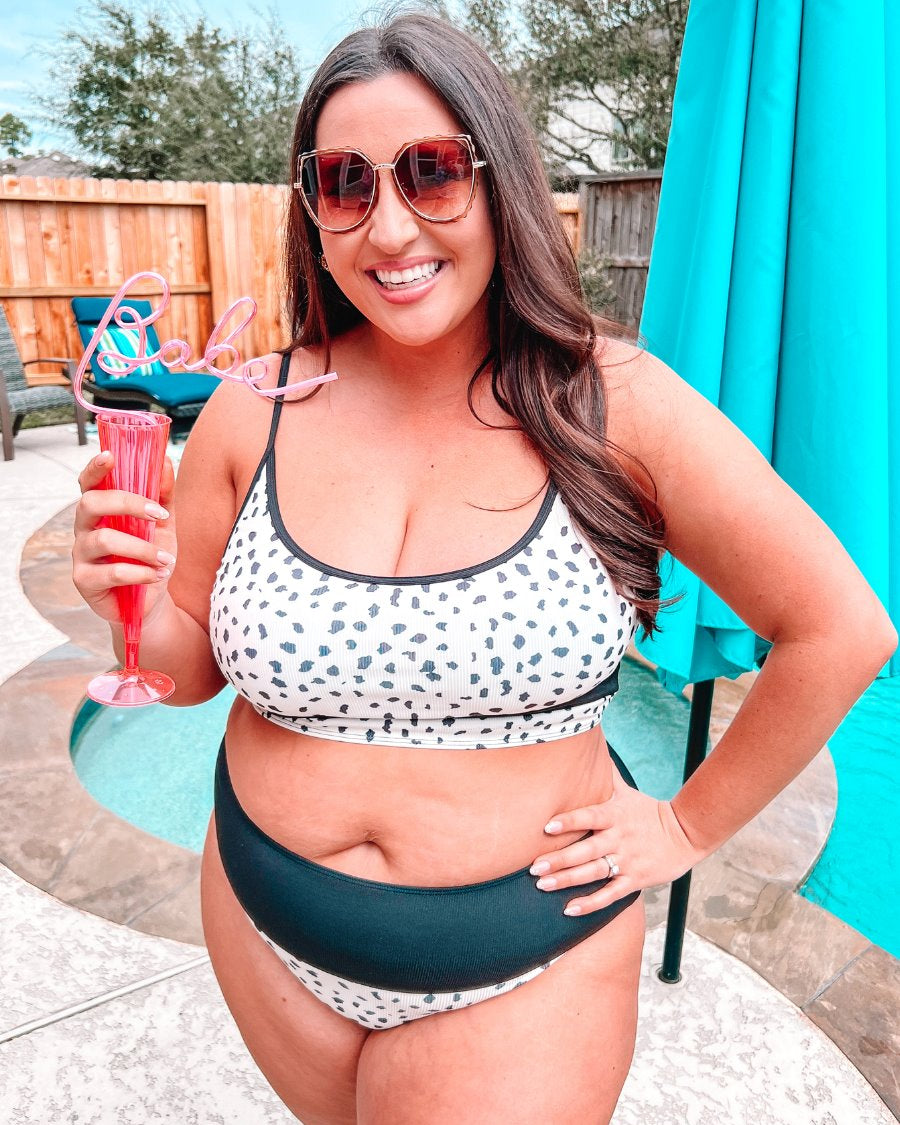 two-piece swimsuit made of lightweight four-way stretchy material and subtle ribbed texturing on a neutral leopard print with a bralette-style top, adjustable spaghetti straps, removable padding, a black band, and flattering form-fitting silhouette paired with high waistline bottoms with a black solid band for added tummy control