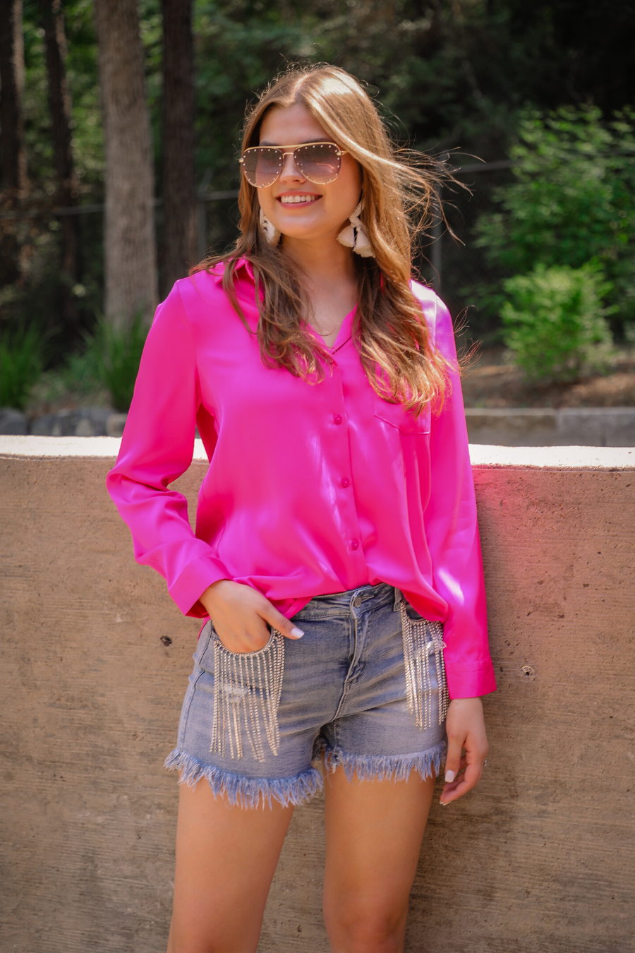 mid-rise denim shorts with rhinestone fringe, a frayed hem, full classic pockets, button zip fly with belt loops, distressed detailing, and a medium wash