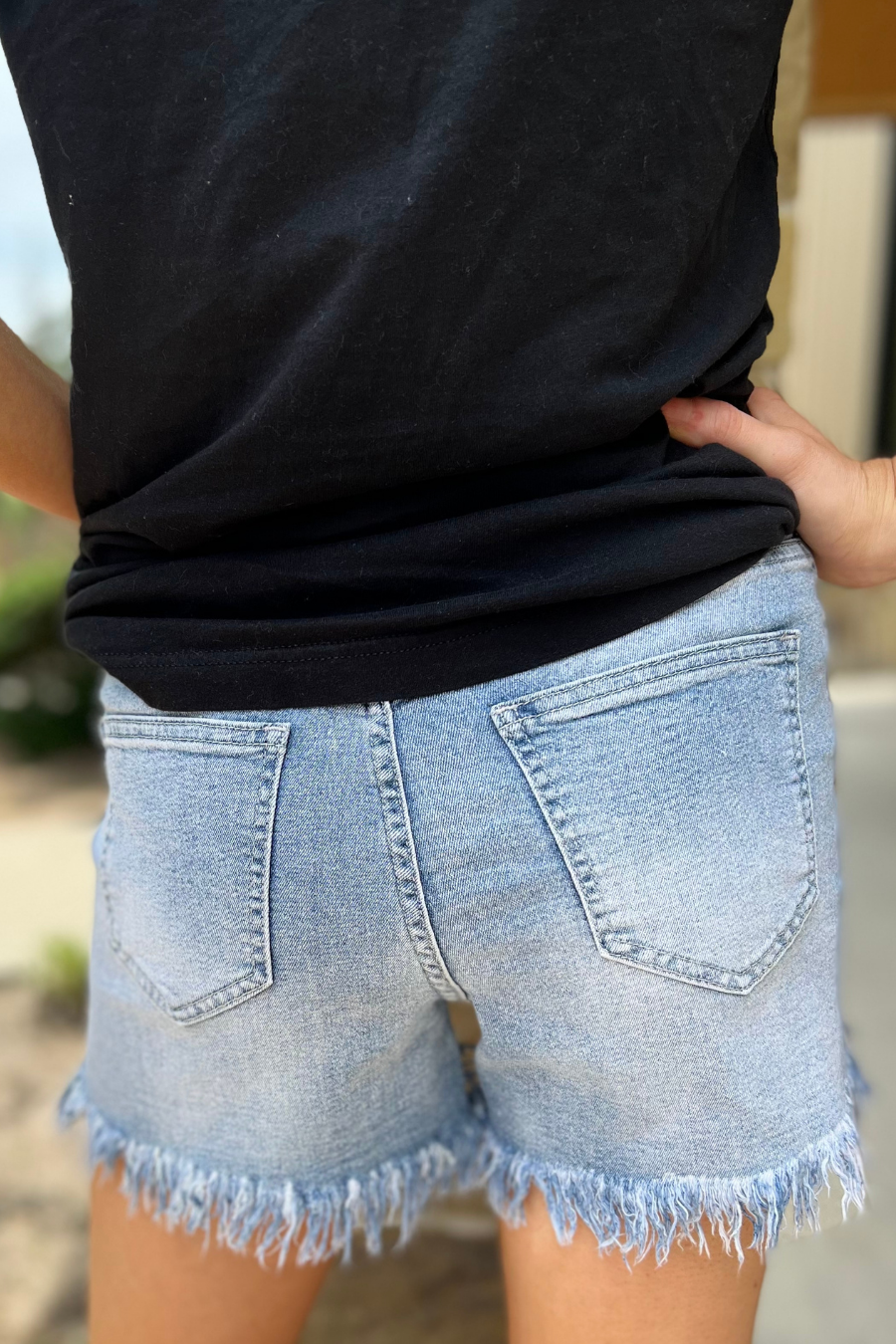 mid-rise denim shorts with rhinestone fringe, a frayed hem, full classic pockets, button zip fly with belt loops, distressed detailing, and a medium wash