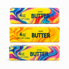 a 4oz butter-stick inspired squishy with a marbled design, salted butter label, soft squeezable texture, and clear individual packaging in colors from top to bottom rainbow swirl (red), citrus swirl (orange), and cotton candy swirl (pink)